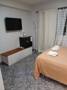 a hotel room with a bed and a flat screen tv at Palmeras II in Vicente López