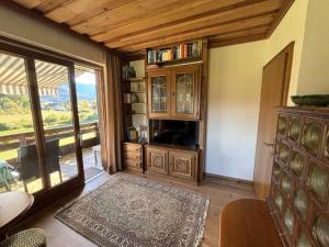 a living room with a tv and a large window at Ferienhaus Sonnhügel - Stissen in Faak am See