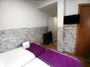 a bedroom with a bed with purple sheets and a tv at Habitaciones El Escorial in Majadahonda