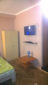 a room with a table and a tv on a wall at Dolce Rita Apartman in Budapest