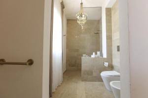 a bathroom with a toilet and a shower and a chandelier at Villa Nivara in Floridia +38 photos
