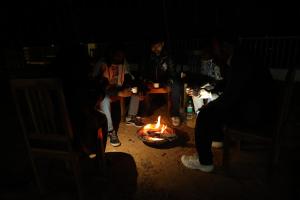 a group of people sitting around a fire in the dark at Monkey River Resort Madla in Rājgarh
