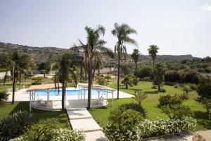 a resort with a swimming pool and palm trees at Villa Nivara in Floridia