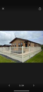 a house with a white fence in front of it at Lazy Days Lodge in Malton