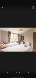 a bedroom with two white beds and a window at Lazy Days Lodge in Malton +7 photos