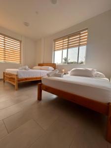 two beds in a large room with two windows at Almar in Olón