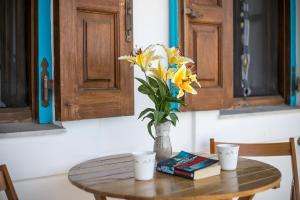 a table with a vase of flowers and books on it at Isminis Villa in Halki