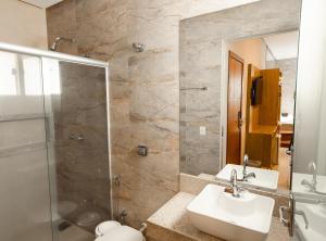 a bathroom with two sinks and a glass shower at Pousada Viver Capitólio in Capitólio