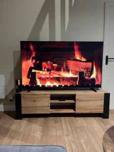 a large television with a fire in a living room at Appartement de Charmes dans le Centre de Cherre in Cherré