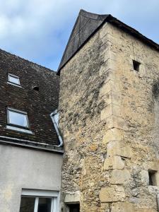 a building with a stone chimney on the side of it at Appartement de Charmes dans le Centre de Cherre in Cherré