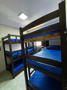 a room with two bunk beds with blue sheets at Sobrados Novos Litoral Norte Caraguatatuba, a 150 m a pe da Praia das Palmeiras, Ar condicionado, WiFi gratis, Churrasqueira privativa, Pet friendly, Estacionamento in Caraguatatuba