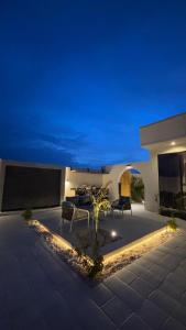 a patio with a table and chairs at night at Areenachalet in Ibrā