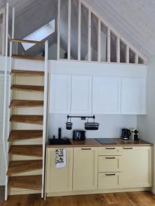 a kitchen with white cabinets and a spiral staircase at Salmistu Saunamaja in Salmistu +10 photos