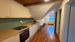 a kitchen with white cabinets and a wooden floor at Ferienwohnung Roseggersiedlung in Murau