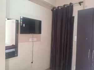 a room with a tv and a black curtain at Krishna Homestay in Bhowāli +14 photos