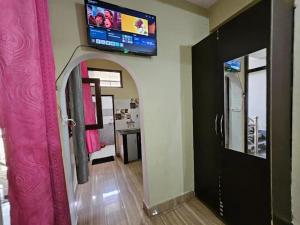 a living room with a tv on the wall and a door at Krishna Homestay in Bhowāli