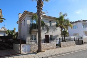 a white house with palm trees and a fence at GREAT VILLA MARIA in Paralimni