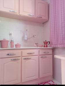 a white kitchen with white cabinets and pink curtains at Casa Rosa in Frederico Westphalen