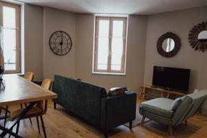 a living room with a couch and a table and a television at Les Suites Gueguen in Chablis