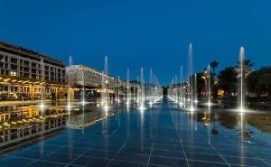 a street with a fountain in a city at night at "Le Zen" by EnjoyNice, central spacious apartment with Airco, beach at 10 min in Nice