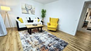 a living room with a couch and a table and a yellow chair at Ioana Homes Ferienwohnung in Abstatt