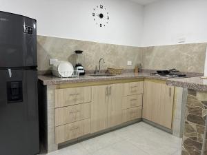 a kitchen with wooden cabinets and a black refrigerator at Coral del mar in Tolú +6 photos