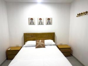 a bedroom with a white bed with two night stands at Coral del mar in Tolú