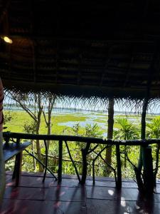 a bench on a porch with a view of a field at Lakeview Birdsong Cabanas in Debarawewa