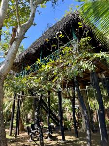 a bamboo hut with trees in front of it at Lakeview Birdsong Cabanas in Debarawewa