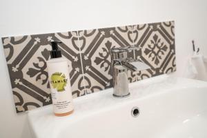 a bathroom sink with a bottle of shampoo and a soap dispenser at Apartment ONE in Sherborne