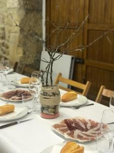 a table with plates of food and a vase with branches at Hostal Restaurante Casa Santamaria in Doneztebe