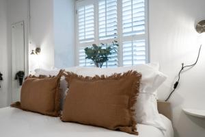 a white bedroom with pillows on a bed with a window at Apartment ONE in Sherborne +4 photos