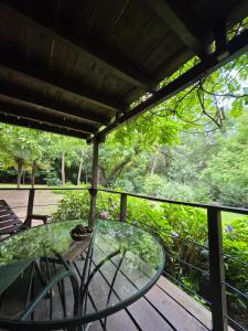a glass table and chairs on a wooden deck at Hotel Loma Bola in La Paz