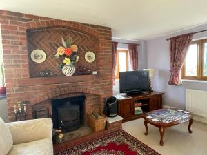 a living room with a brick fireplace with a tv at Hardy View Farm House in Dorchester