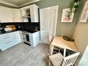 a kitchen with white cabinets and a table and a door at Island View in Benllech