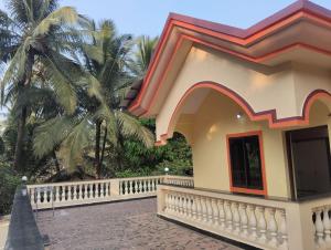a house with a fence and a palm tree at Grace Green Holiday Home in Benaulim