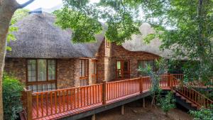a house with a thatched roof and a deck at Kruger Park Lodge Unit No 219 in Hazyview