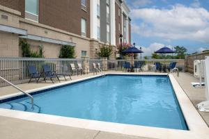 a large swimming pool with chairs and a building at Hampton Inn & Suites Holly Springs in Holly Springs