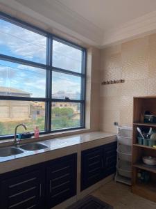 a kitchen with a sink and a large window at Dares Salaam in Cotonou