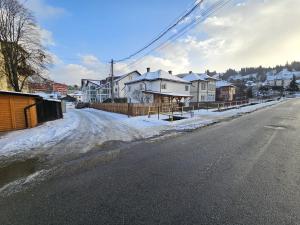 a snowy street with houses on the side of the road at Casa Apartament Refugiul Dornean in Vatra Dornei