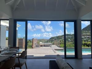 a living room with a view of a pool and a house at Spacious Modern Villa with Pool & Sunrise View - Graviola St Barth in Marigot