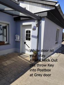 a blue house with a white door and a window at Gästehaus Ruhepol in Bissendorf +2 photos