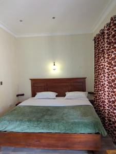 a bedroom with a large bed with a green blanket at Karibu Resort Sipi in Kapchorwa