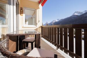 a balcony with a glass table and a window and mountains at Brentsch A27 in Scuol