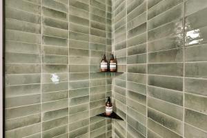 a tiled bathroom with two bottles of alcohol on shelves at Milly Slopeside Studio in Brighton +16 photos