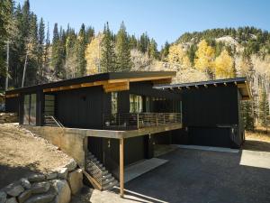 a black house in the mountains with trees at Milly Slopeside Studio in Brighton