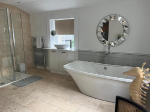 a bathroom with a tub and a shower and a mirror at Giffnock Rooms in Giffnock +13 photos