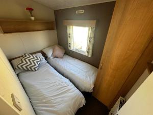 two beds in a small room with a window at Blanco's by the sea in Saint Osyth +11 photos