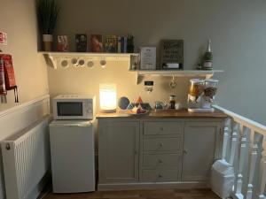 a kitchen with a counter with a microwave and a refrigerator at Giffnock Rooms in Giffnock