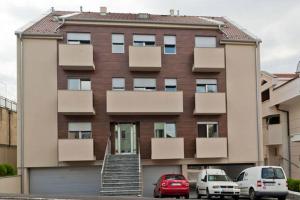 un bâtiment avec deux voitures garées devant lui dans l'établissement Lazic Apartment, à Belgrade